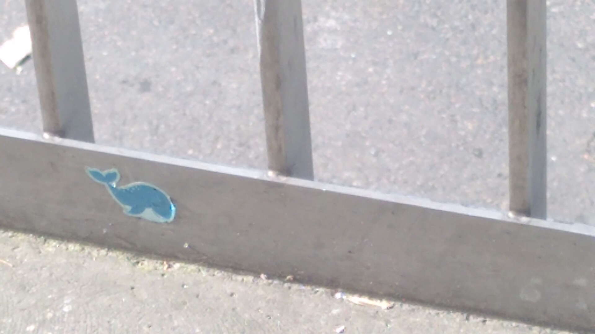 A sticker of a whale at the botton of a metal railing