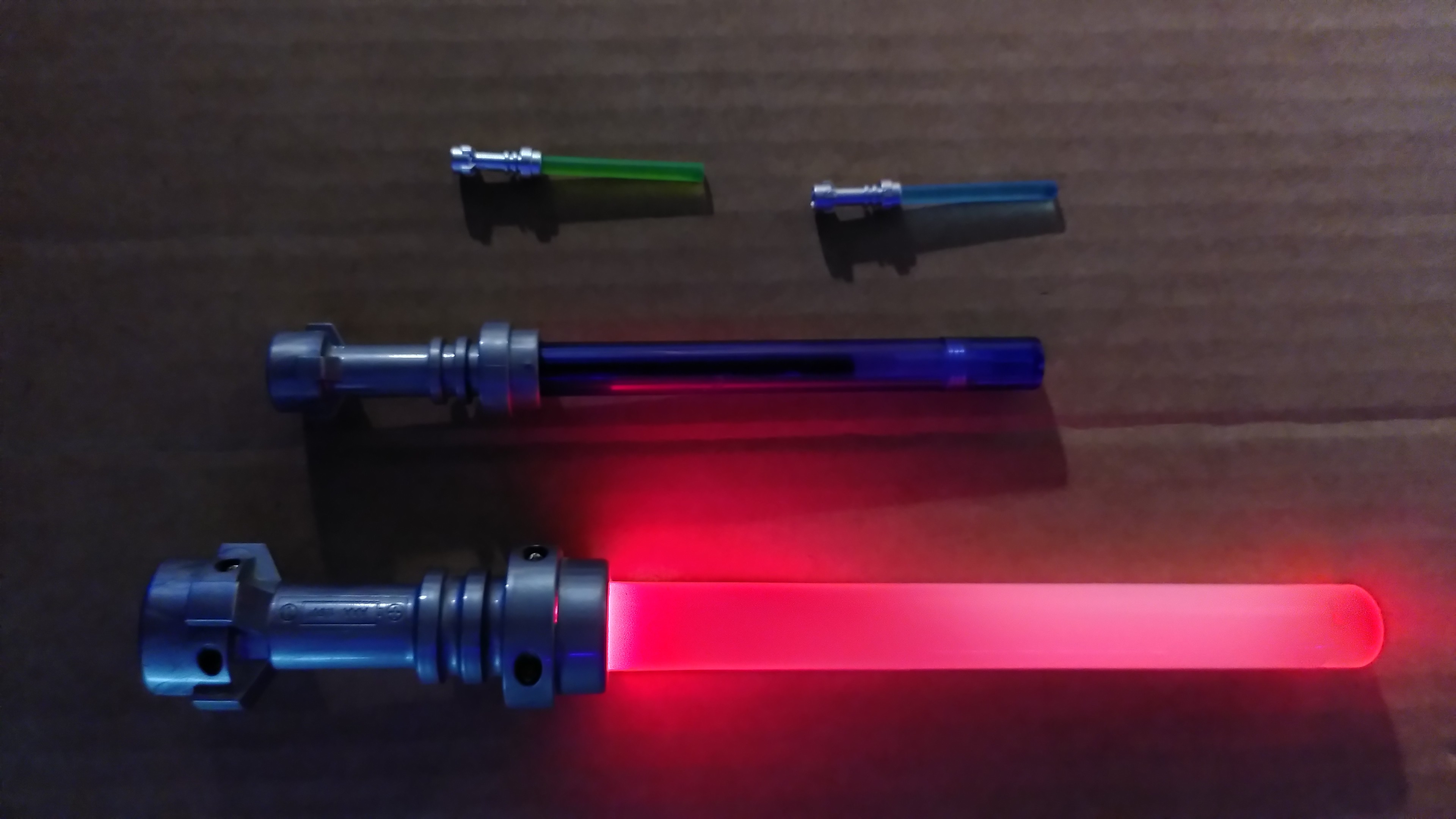 4 lego lightsaber. Top two are minifigurine size green and blue, middle is a purple pencil, with the hilt doubling as the cap, bottom light up, come with a lego dark vador torchlight