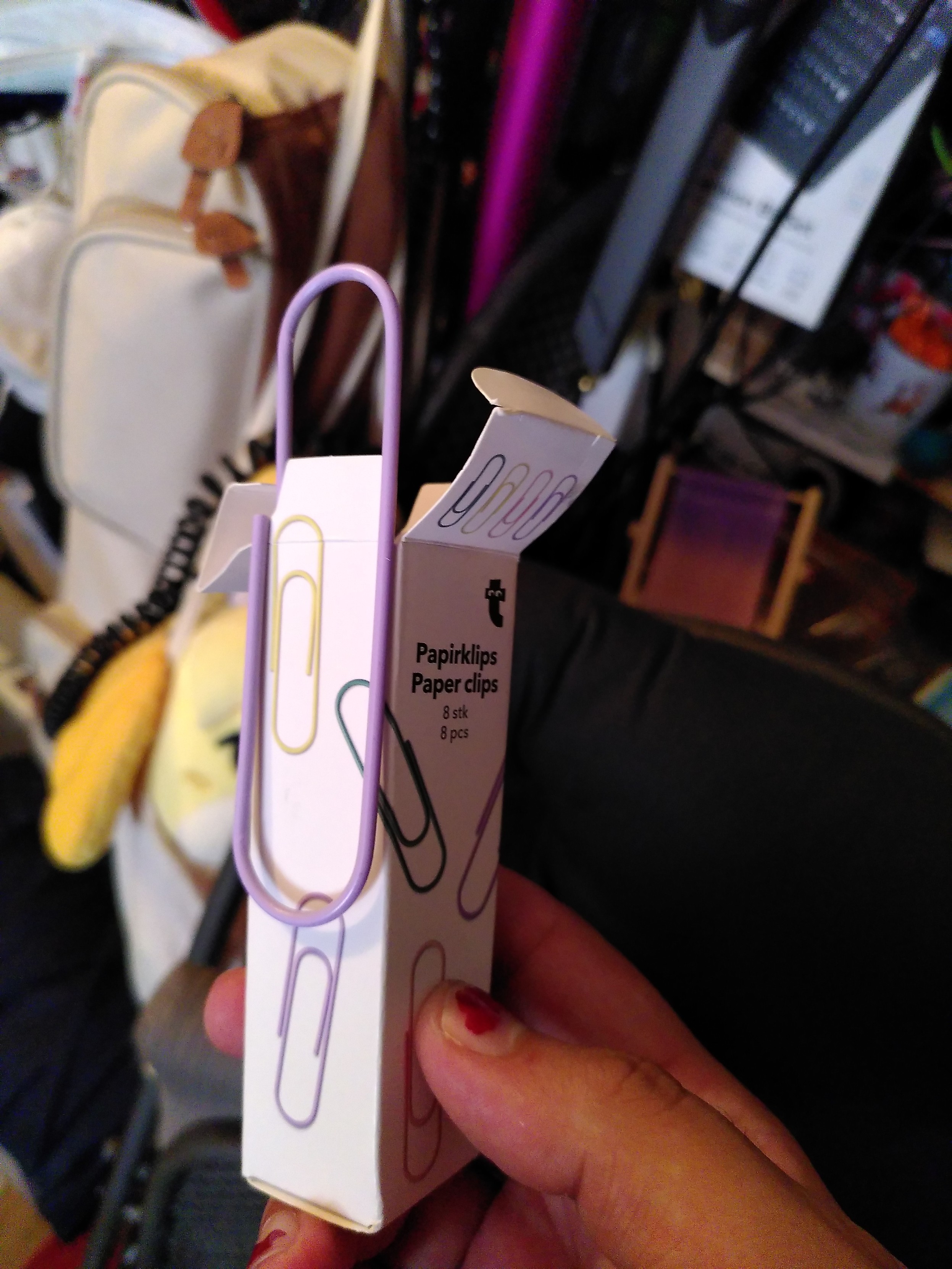 A purple pastel oversized paperclip attached to its box that contain 7 more