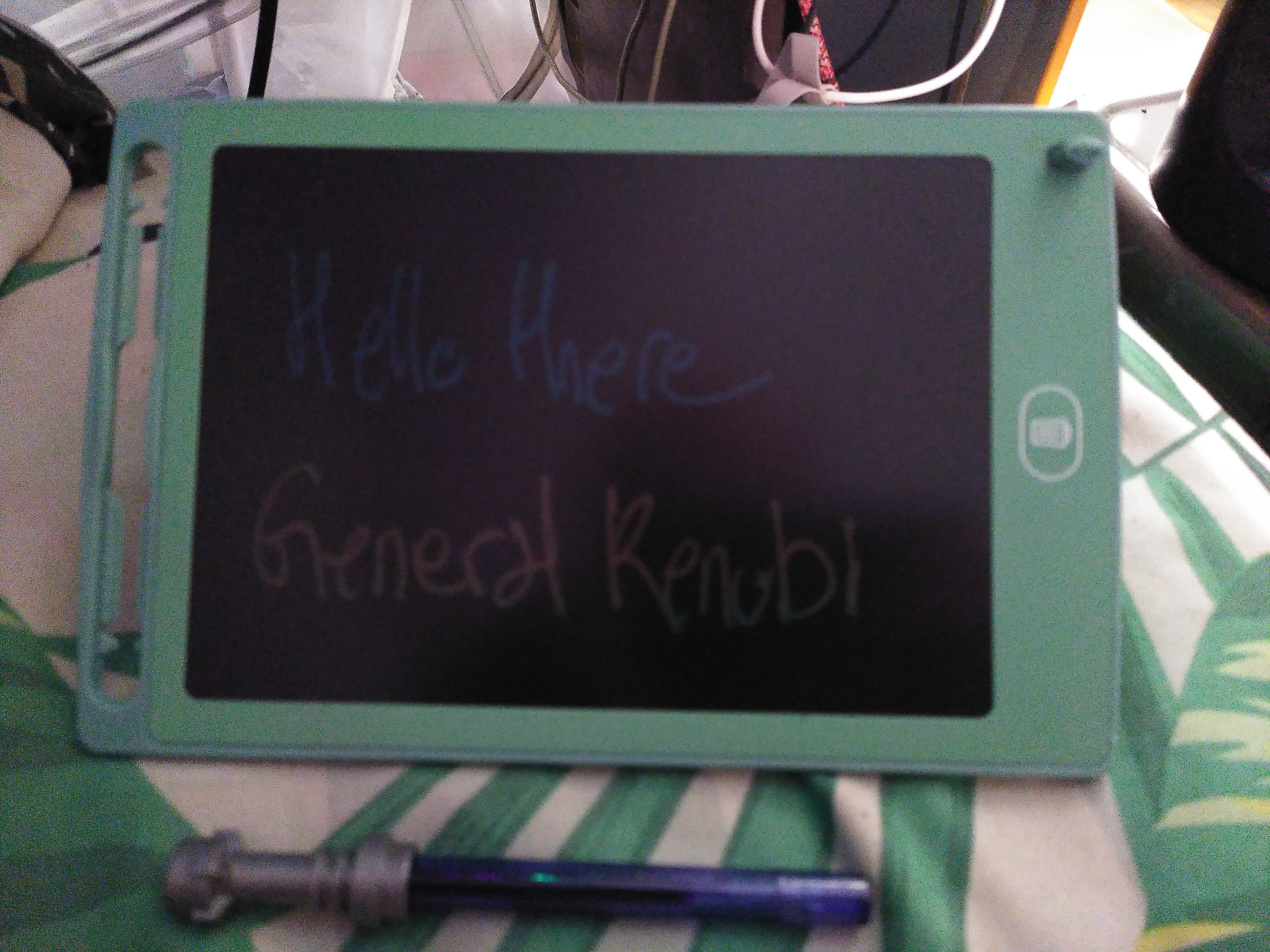 An electronic magic board. It's black with a pastel green frame and its LCD screen turn colorful when something press on the screen. There is a trash can icon that erase the board. On it is written 