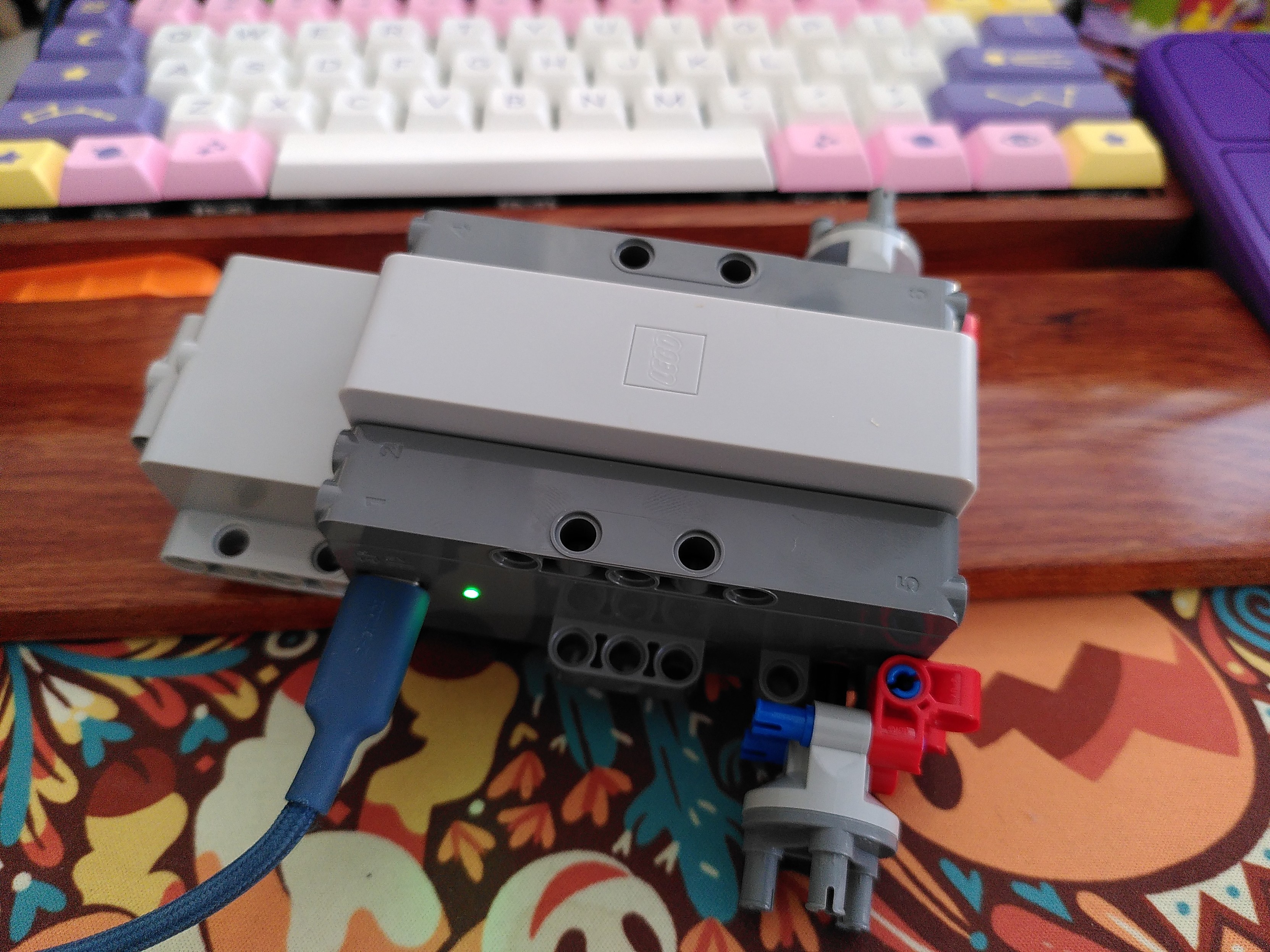 the new lego car controller. It's like a dark gray box with a light gray box  stuck in front and a long thin gray box stuck on top. Top gray part is a removable lithium battery, the front light gray box might be a stepper motor? The dark gray part has an USB C charging port, 2 independent motors with output on the sides and back, 4 independent white led facing front and 2 facing back.
