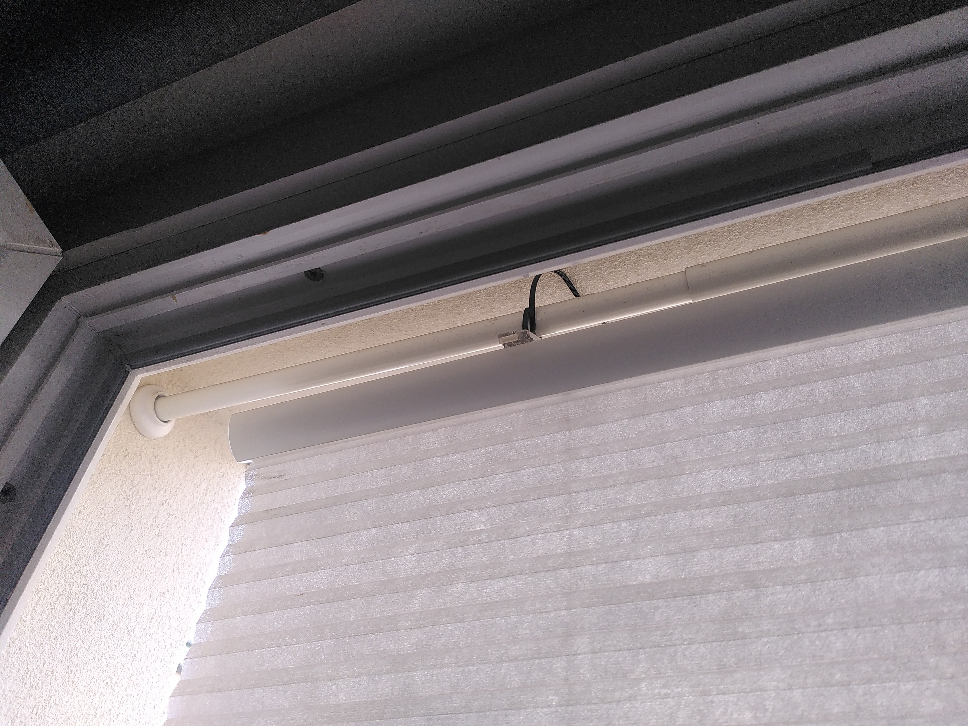 A Trippevals from ikea attaches to a botaren with a black zip tie outside an open window