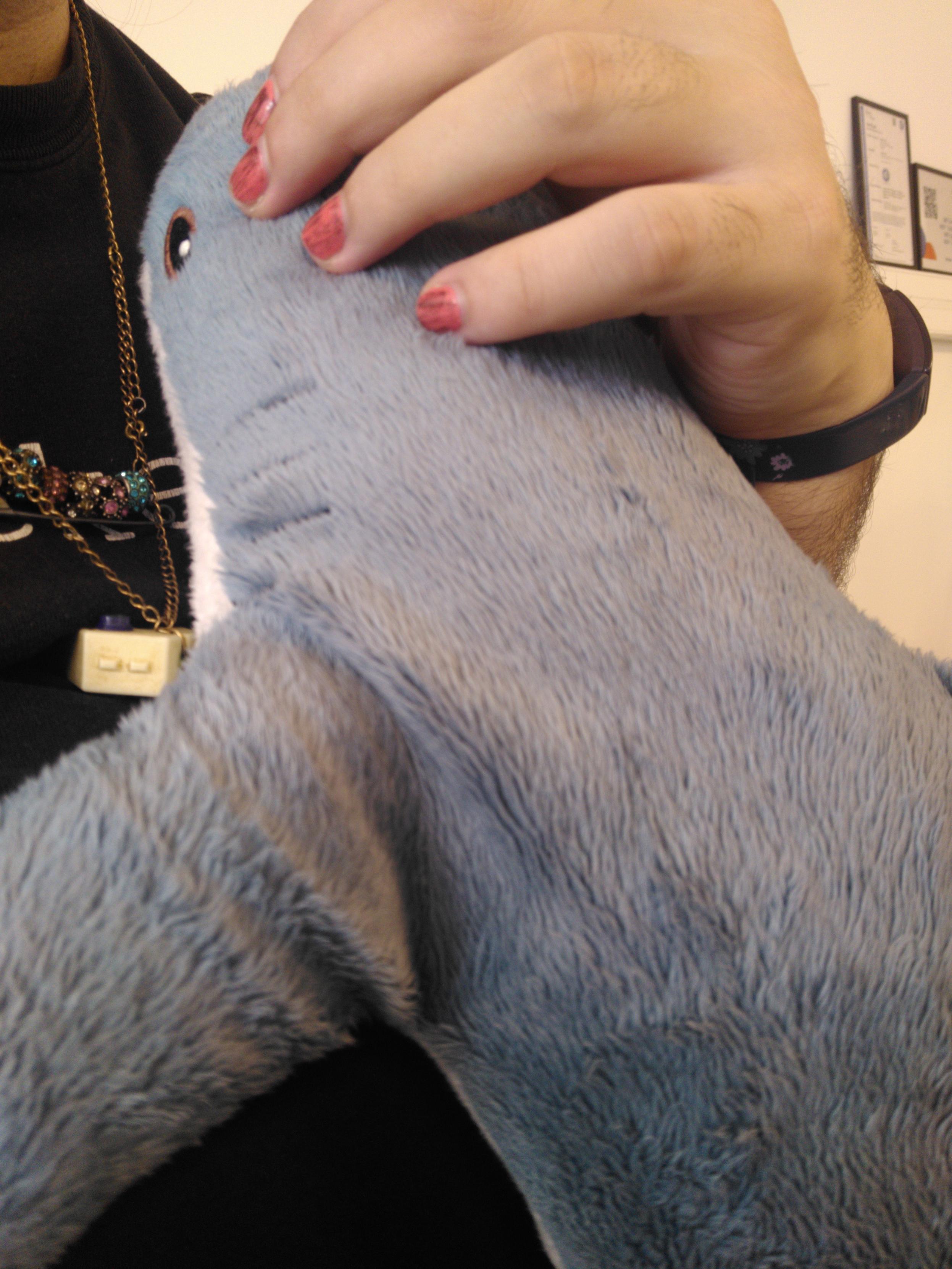 An ikea shark plushie propped against me. My hand is visible on top with 