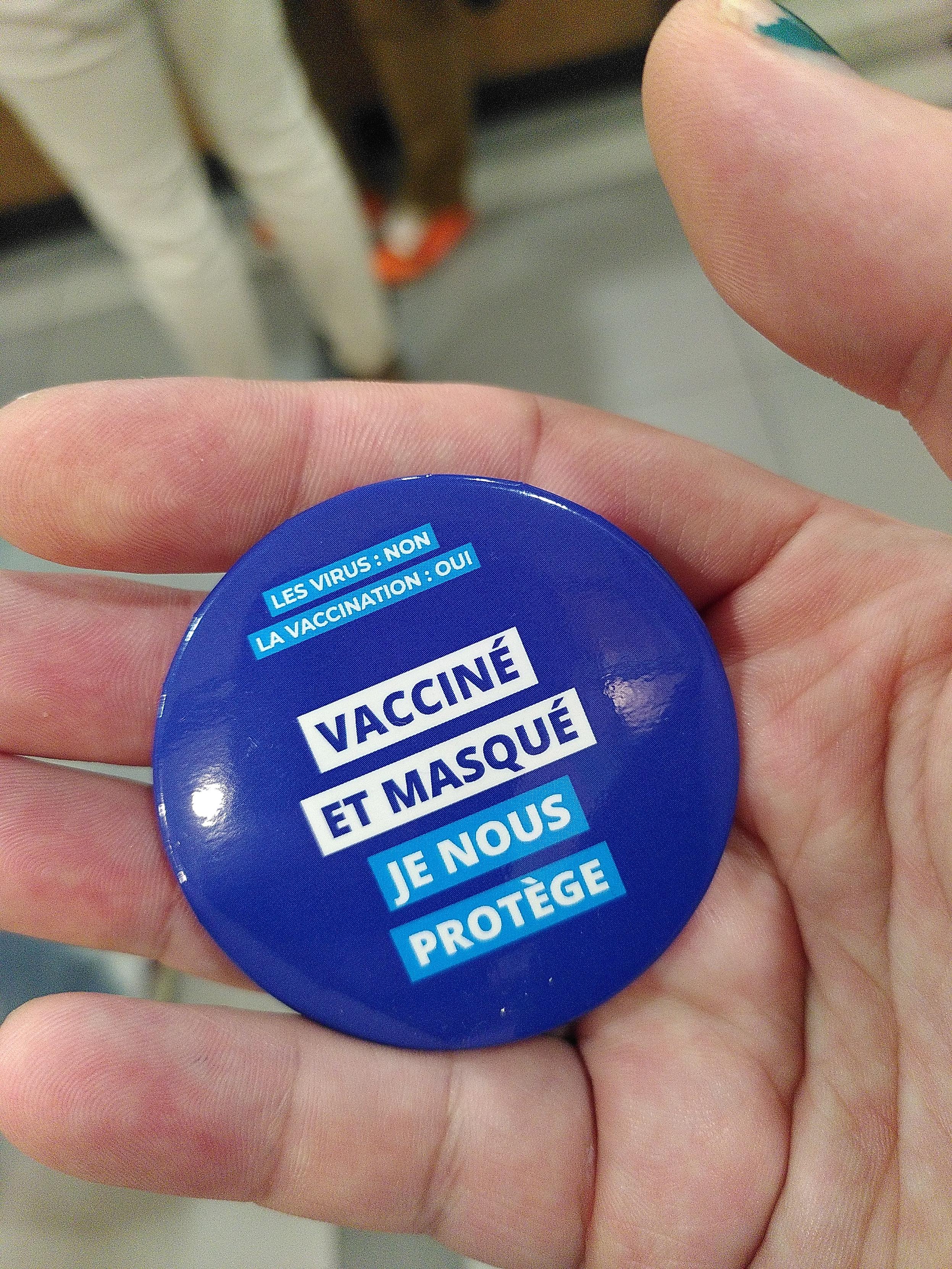 A large round blue pin saying viruses: no, vaccine: yes, vaccinated and masked, I protect us