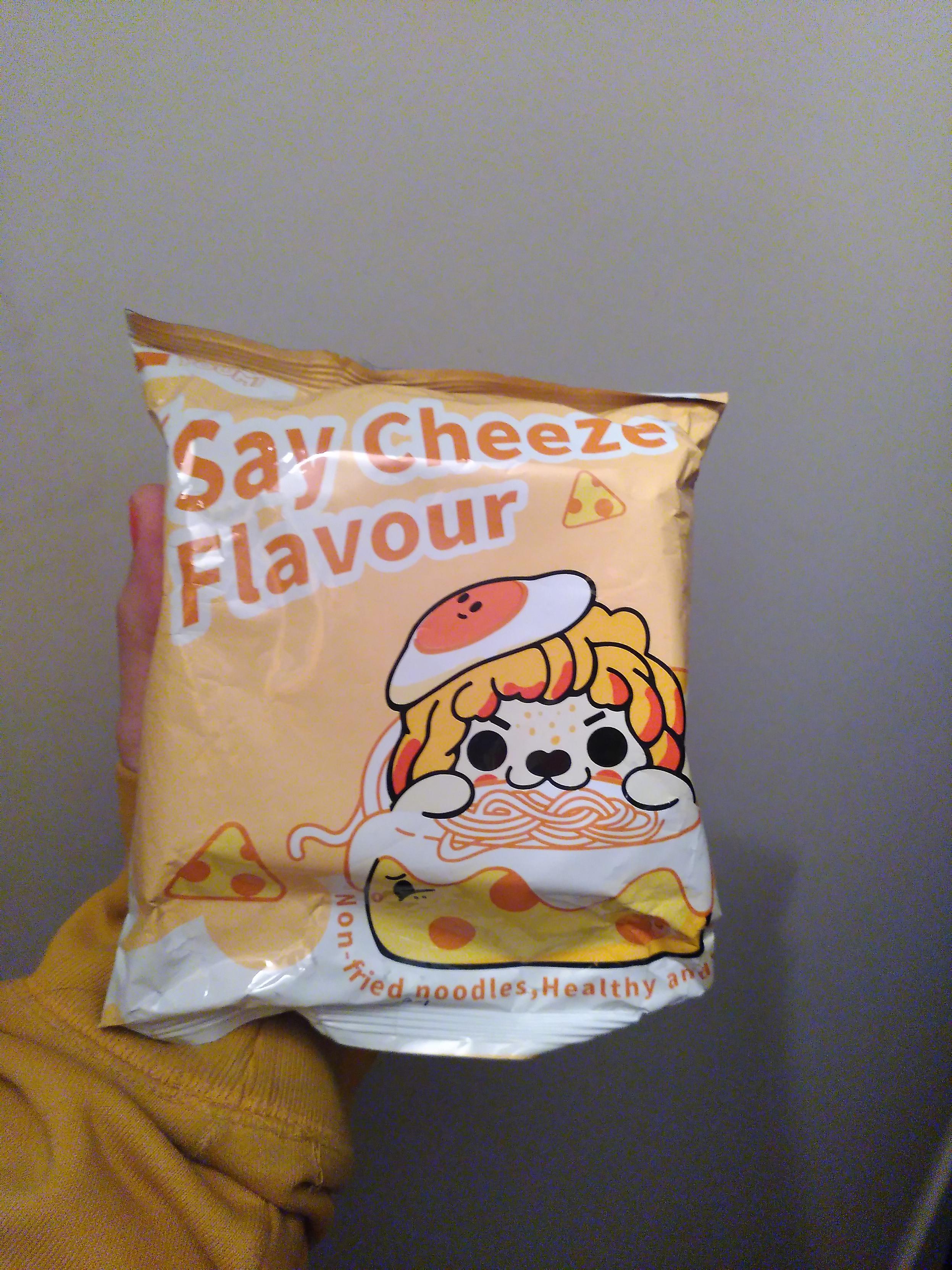 Instant noodle, say cheese flavour. With a dog? mascot eating noodle in a cheese bowl, wearing a fried egg as hat. Both the cheese and egg have a face.