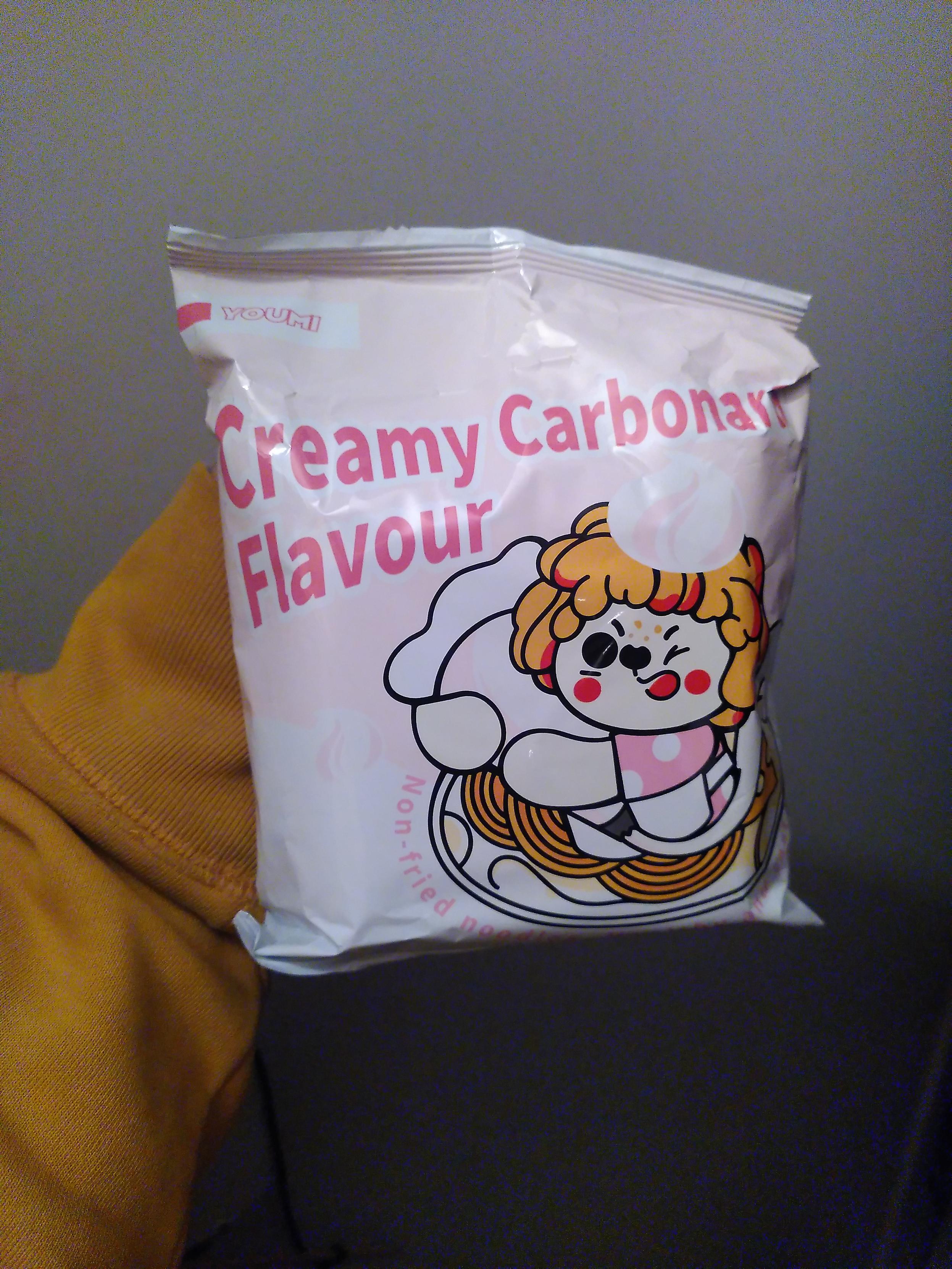 instant noodle, creamy carbonara flavoutlr. With a dog? mascot putting whipped cream? on noodle and cheese