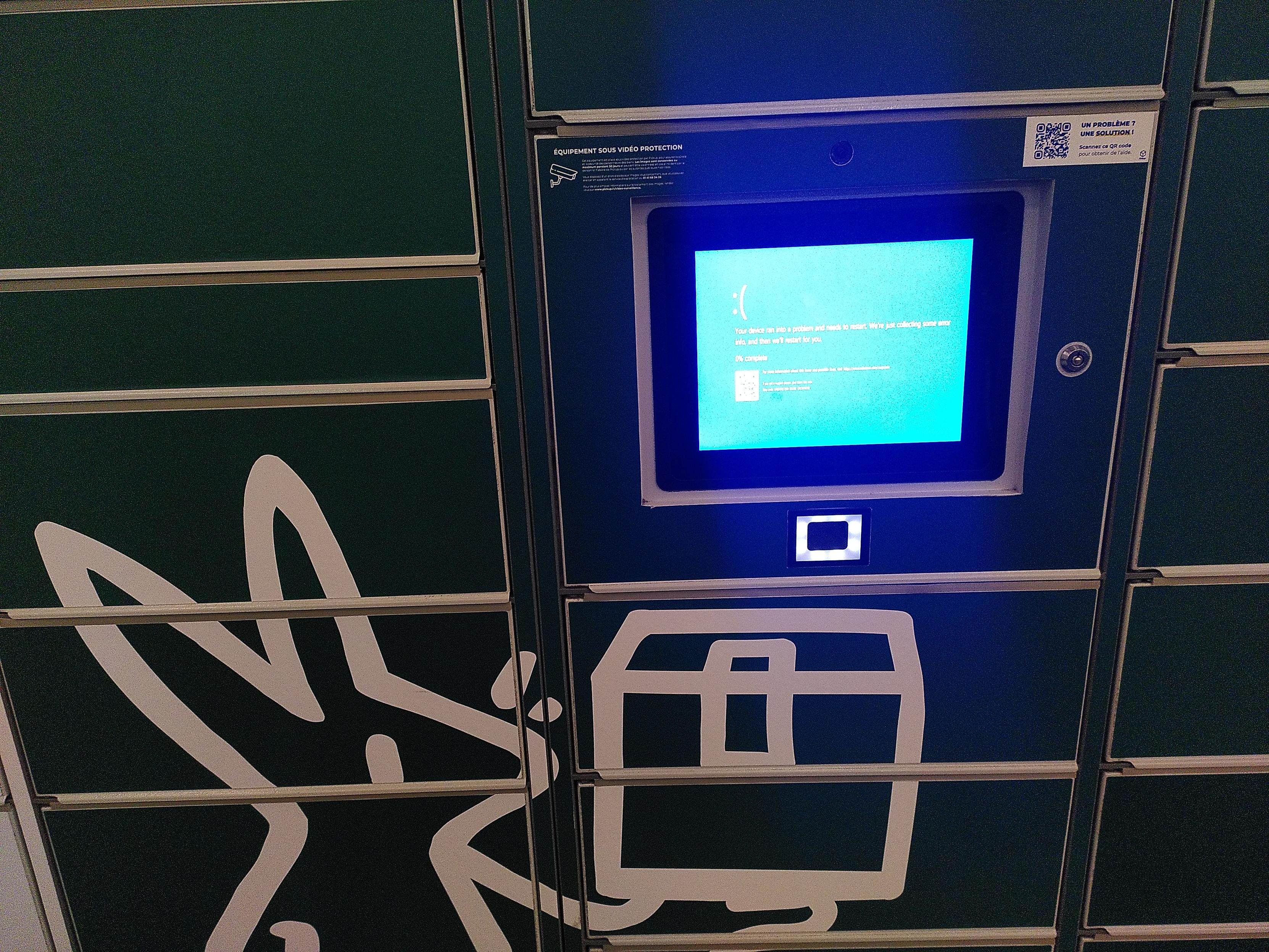 A package self-pickup point, with a touch screen showing a windows blue screen error stuck at 0%