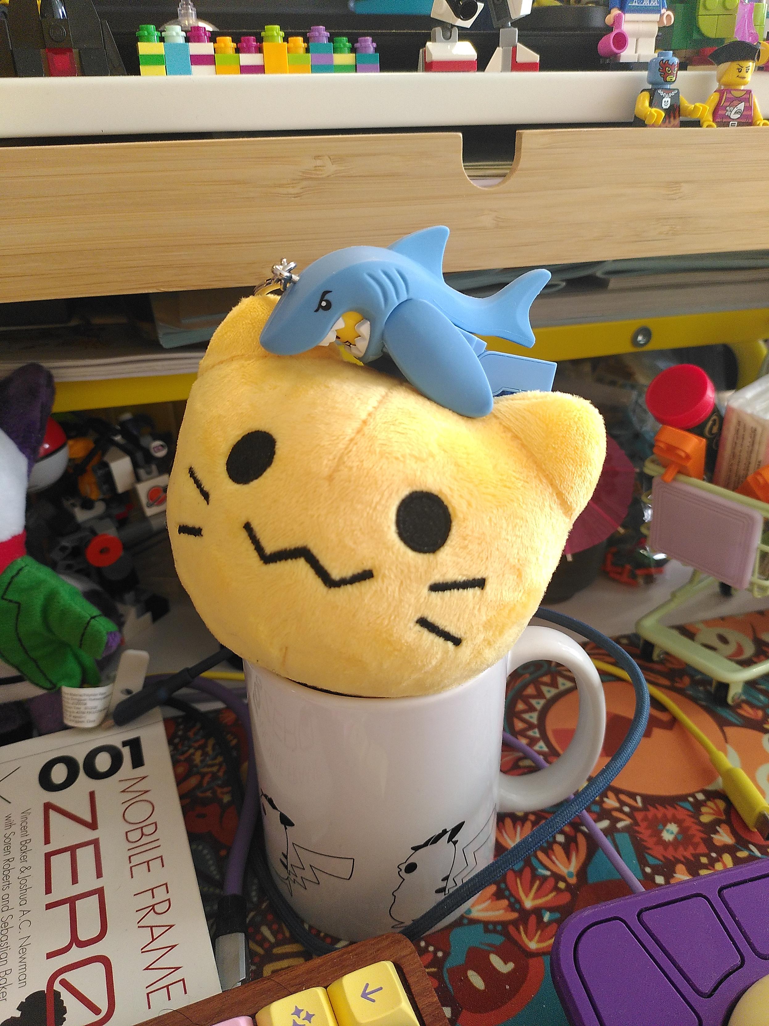 A person in a shark costume lego keyring hugging a blobcat plushie