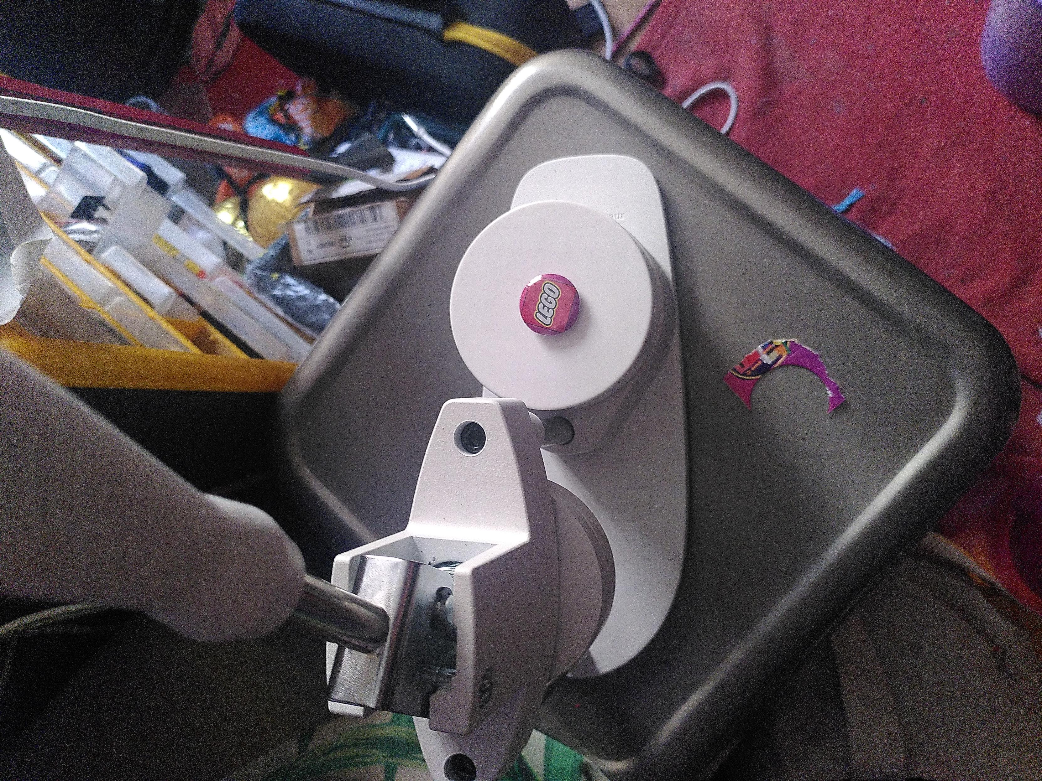 A press to make badge sitting on a metal stool. On the press is sitting badge with the lego logo