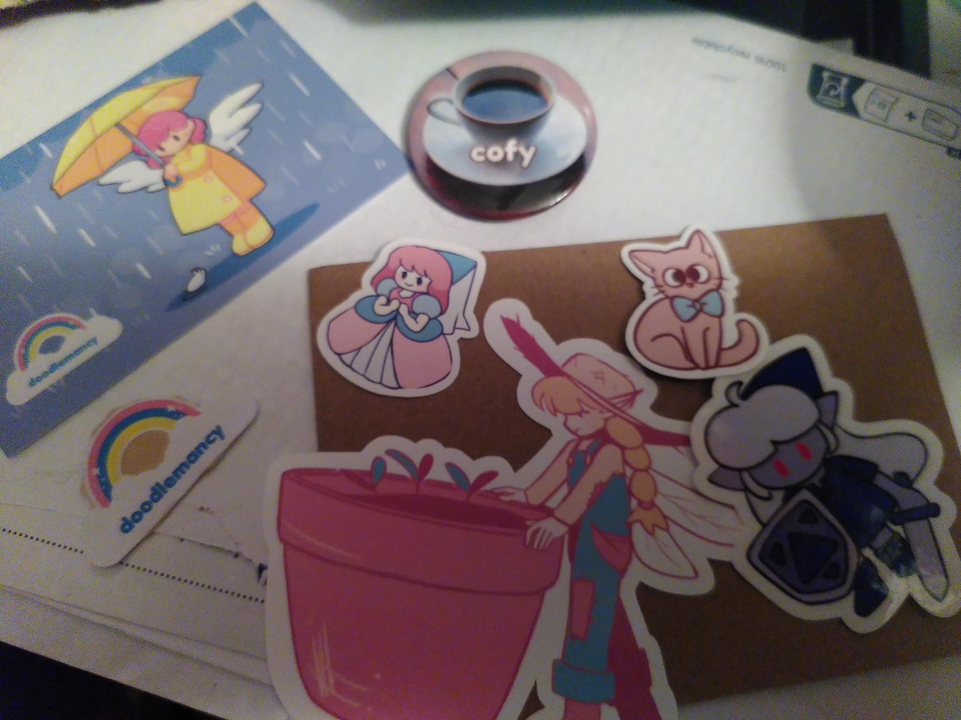 Badly light photo of stickers and a badge from doodlemancy. Sticker are a fairy in farmer outfit taking care of a flower pot half their size, a legendary girl but evil (link to the past design with with long hair and ocarina of time dark link color scheme), a princess and a cat with a bow tie. The badge is a photo of a coffee cup with written in a round font 