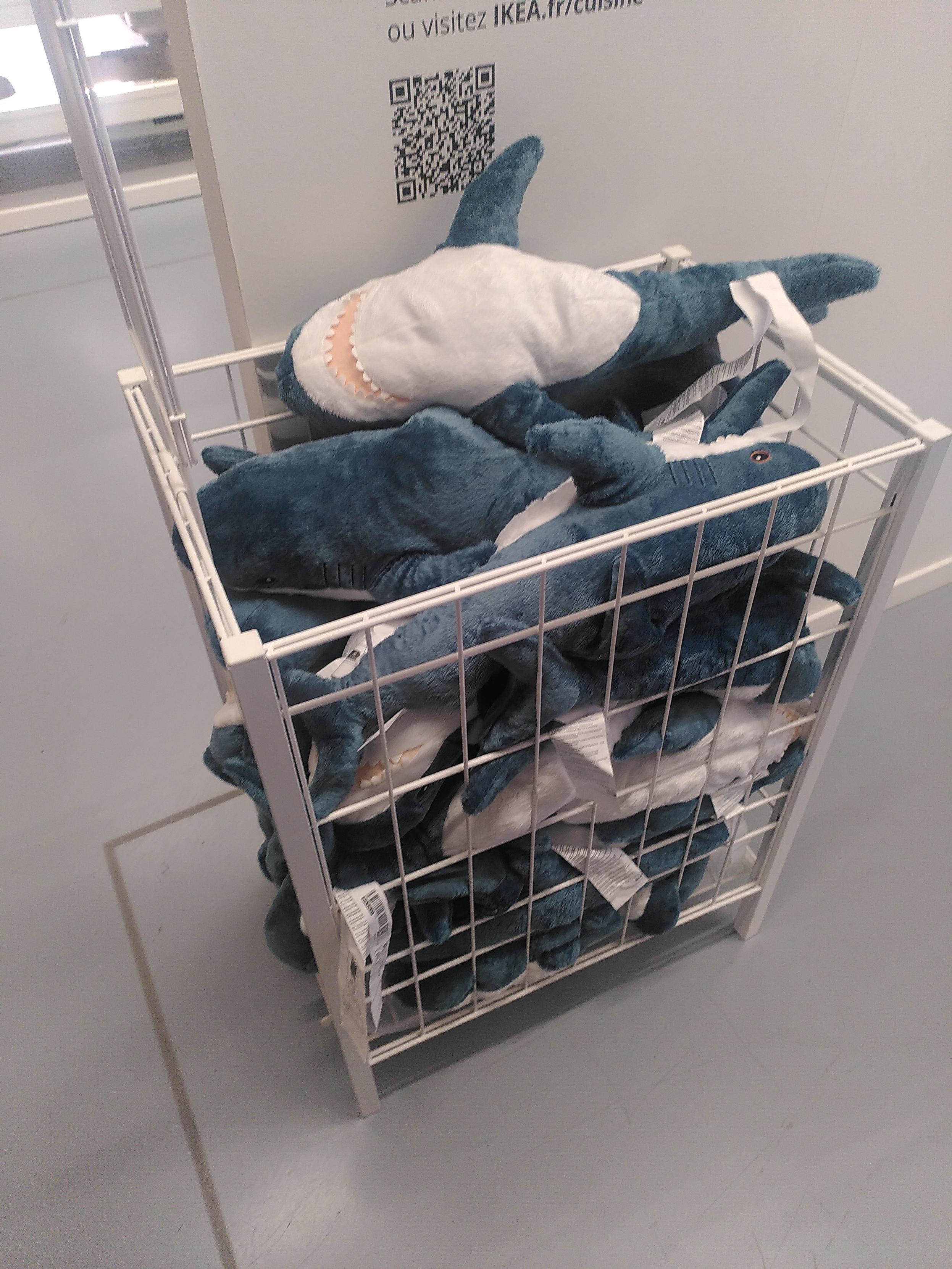 A stack of shark plushie in a cage