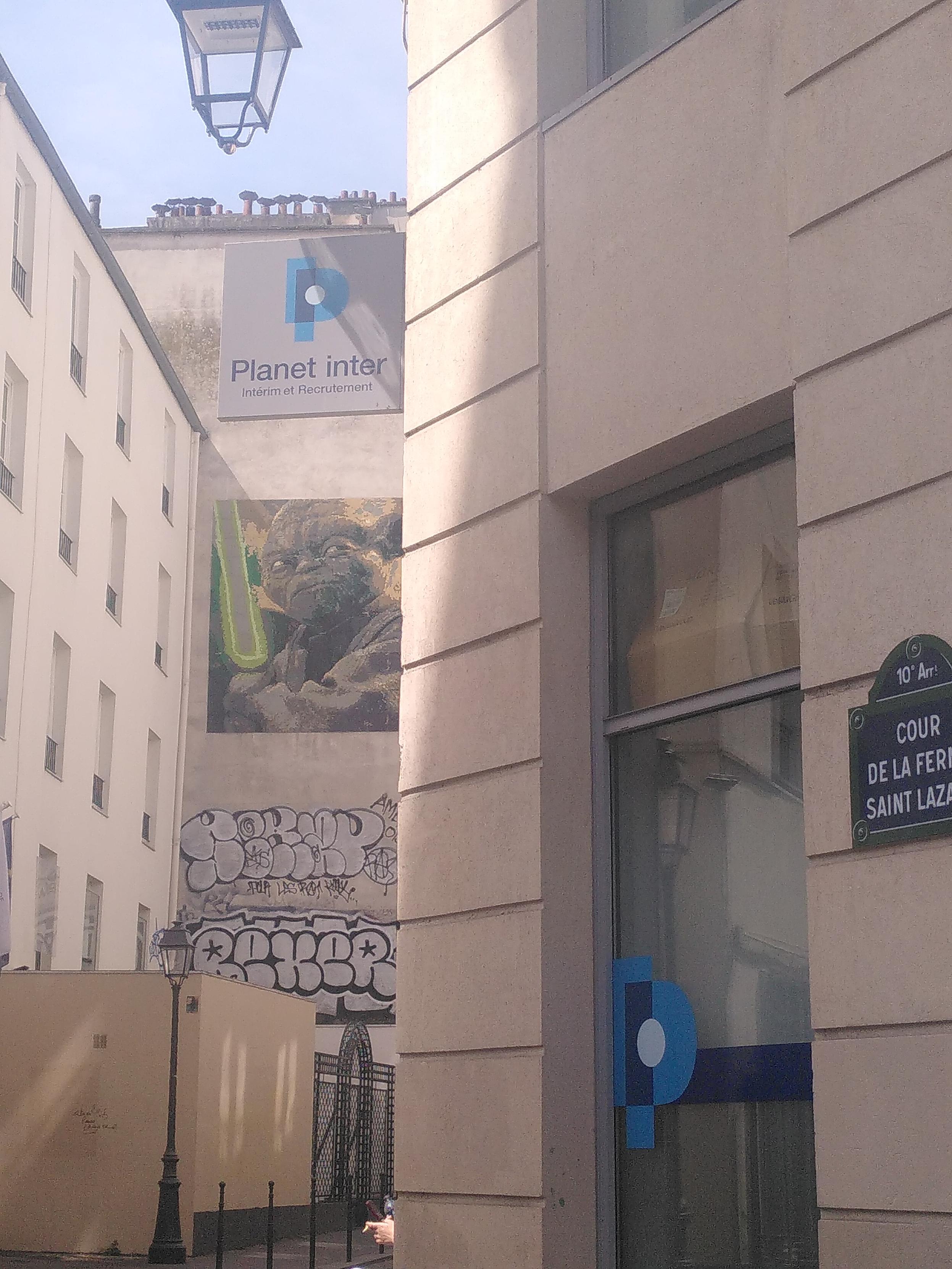 Exterior photo in paris. In the background, maybe 6 meters above the ground is a large mosaic depicting yoda, light saber in hand