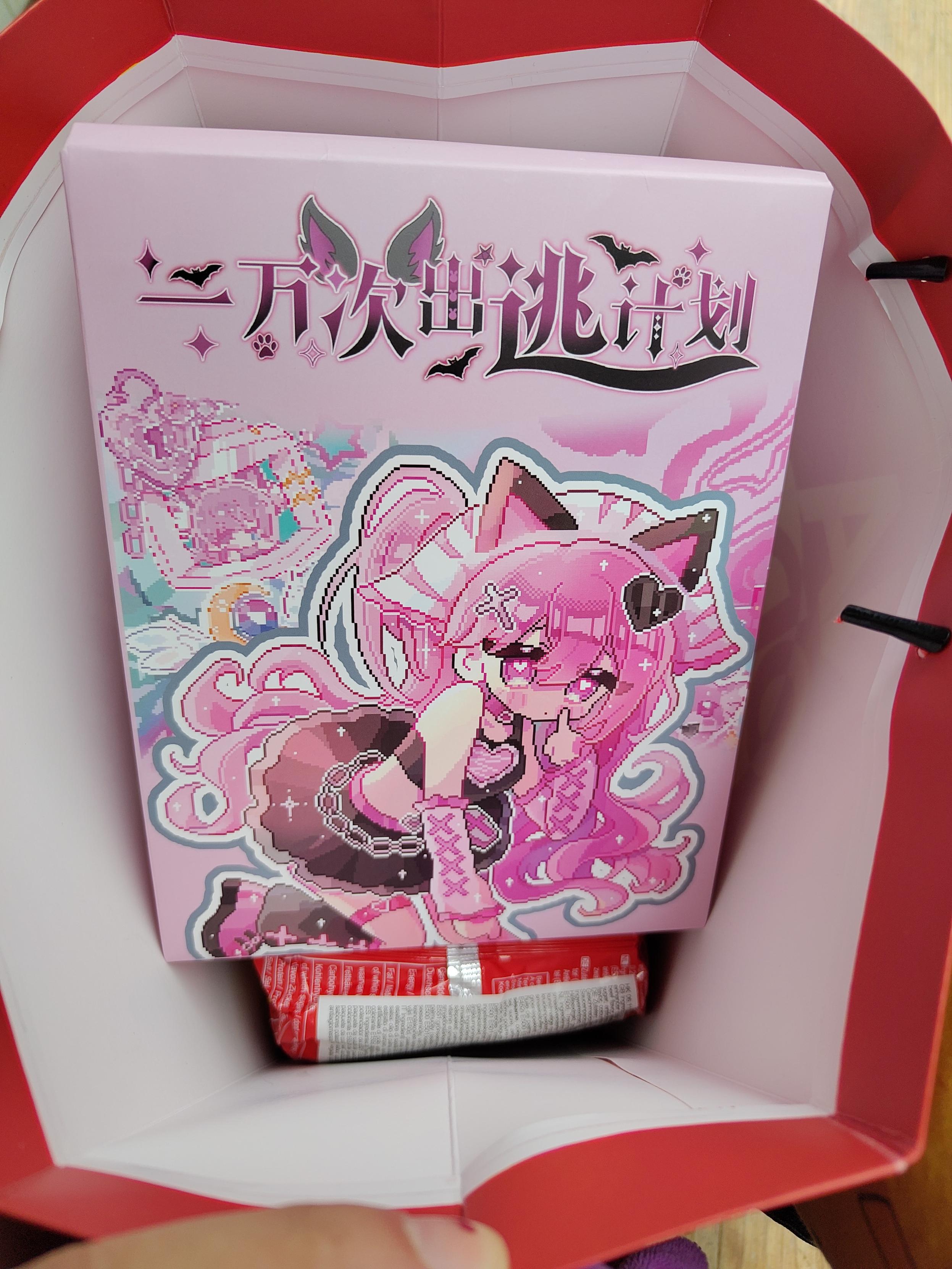 Photo of a blind box, slightly bigger than my hand. The illustration is all pink with some blue accent, featuring a pixel art cat girl with long bright pink hair and a title written in east-asian character